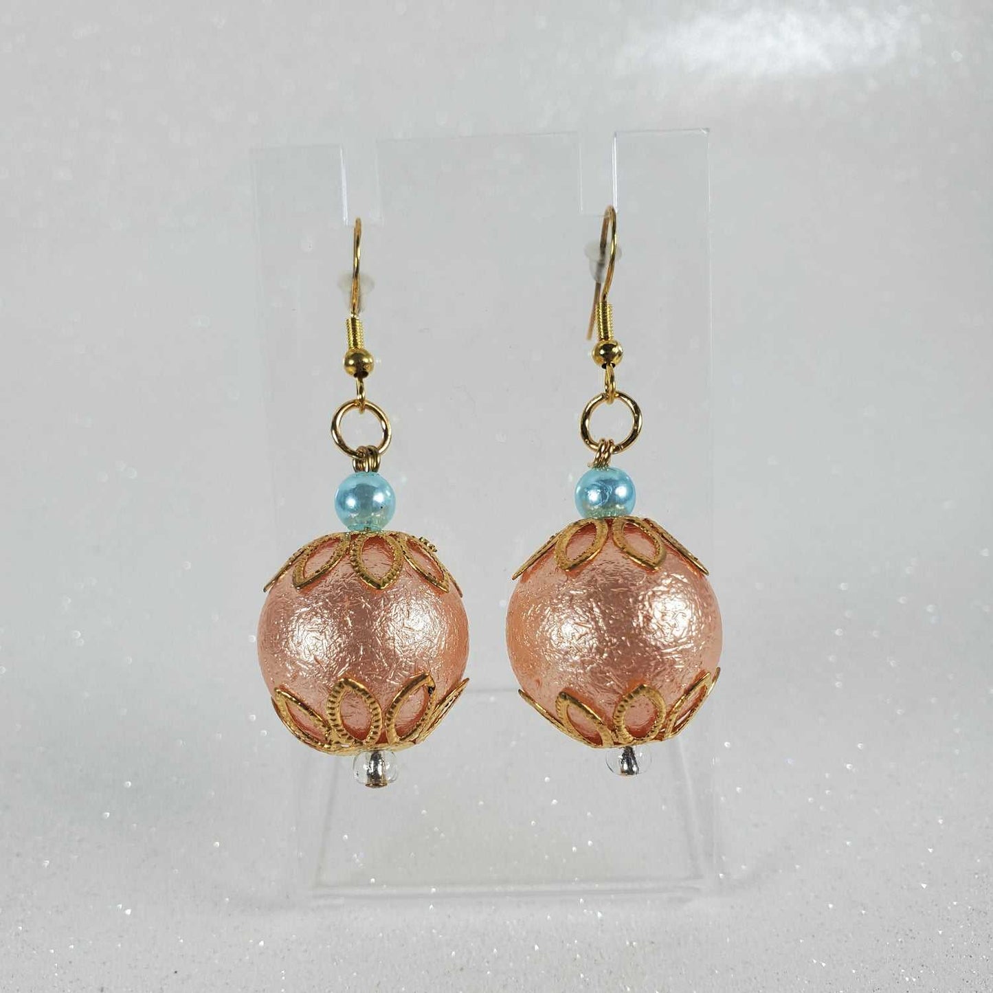 Pair of peach beaded earrings with gold hooks on a light gray background