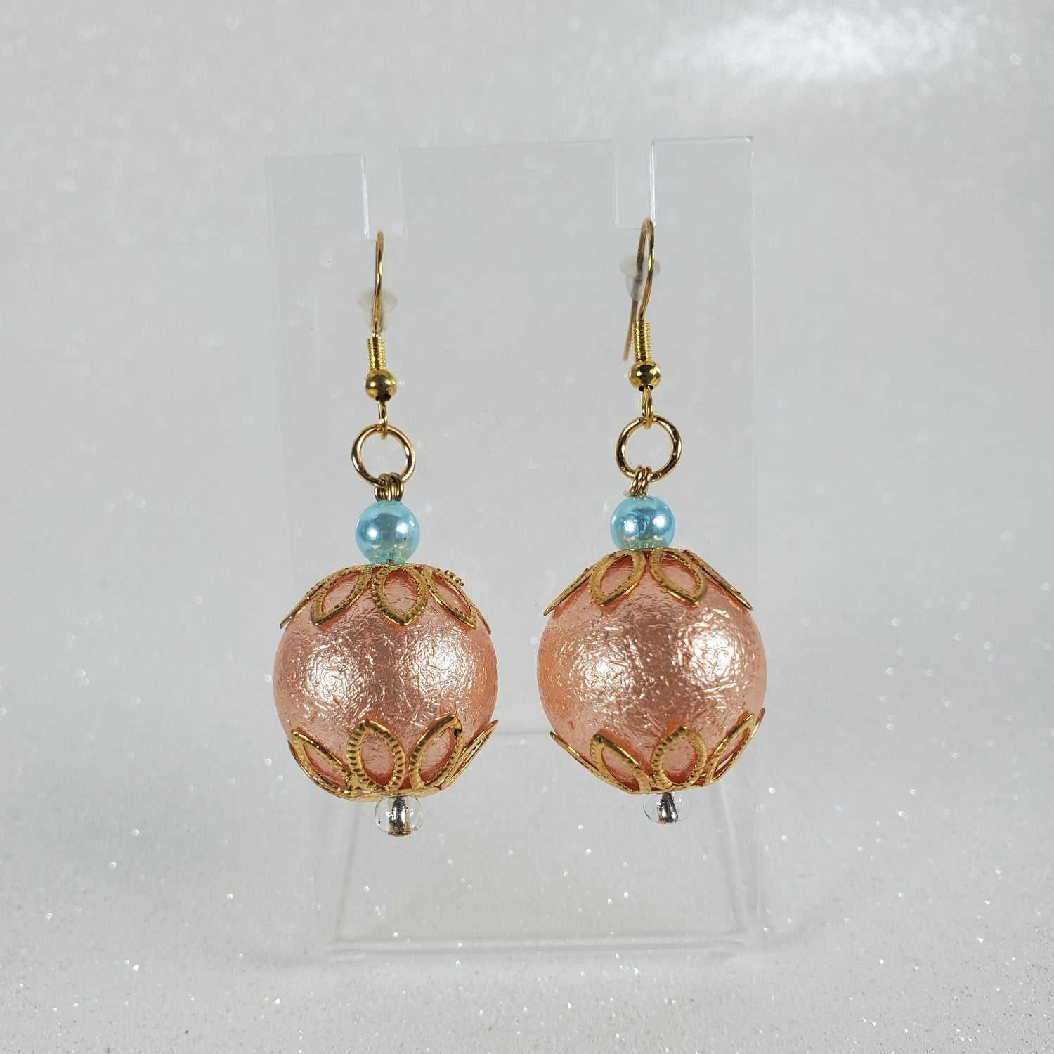 Pair of peach beaded earrings with gold hooks on a light gray background