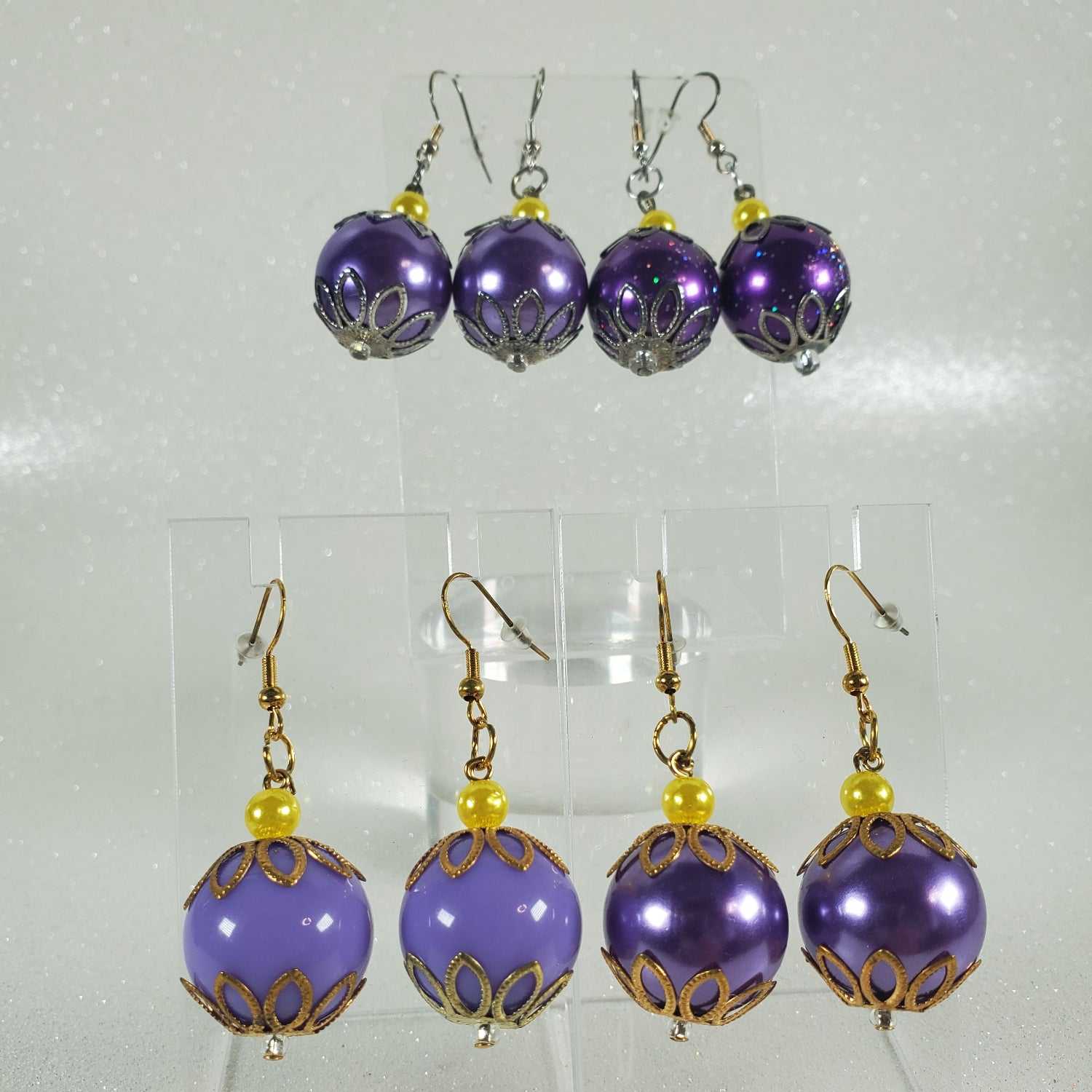 Set of purple beaded earrings with gold accents on a clear background