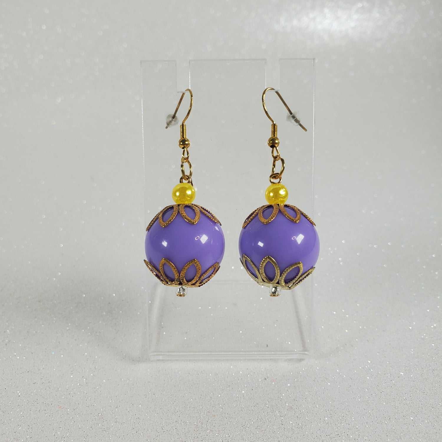 Purple round earrings with gold accents on a gray background