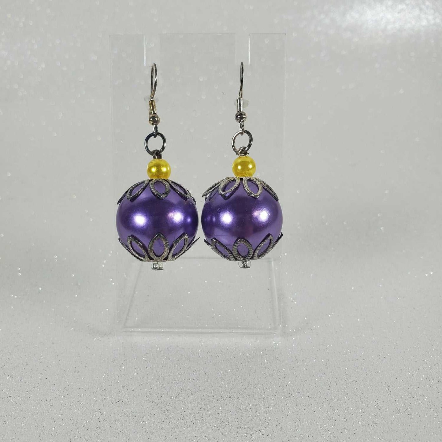Purple beaded earrings with gold accents on a gray background