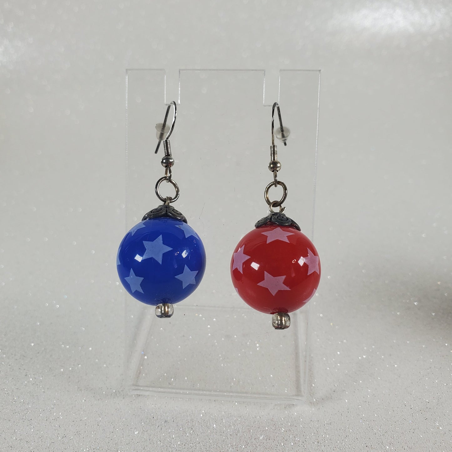 Pair of earrings with red and blue beads on a clear background