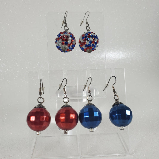 Pair of blue and red beaded earrings on a clear stand against a gray background