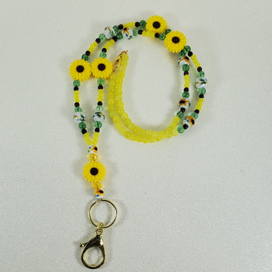 Yellow beaded lanyard with sunflower designs on a light gray background