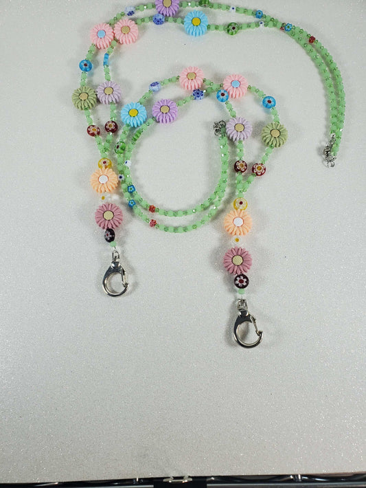 Colorful Daisy Daze lanyard with pastel polymer daisy beads and green glass accents, 30-inch handmade floral accessory with metal clasps.