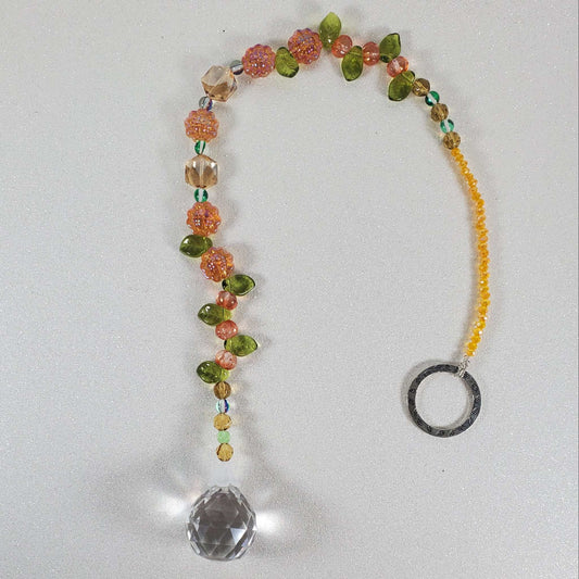 Crystal suncatcher with orange sunflower beads, green accents, yellow crystals, and a clear drop prism.