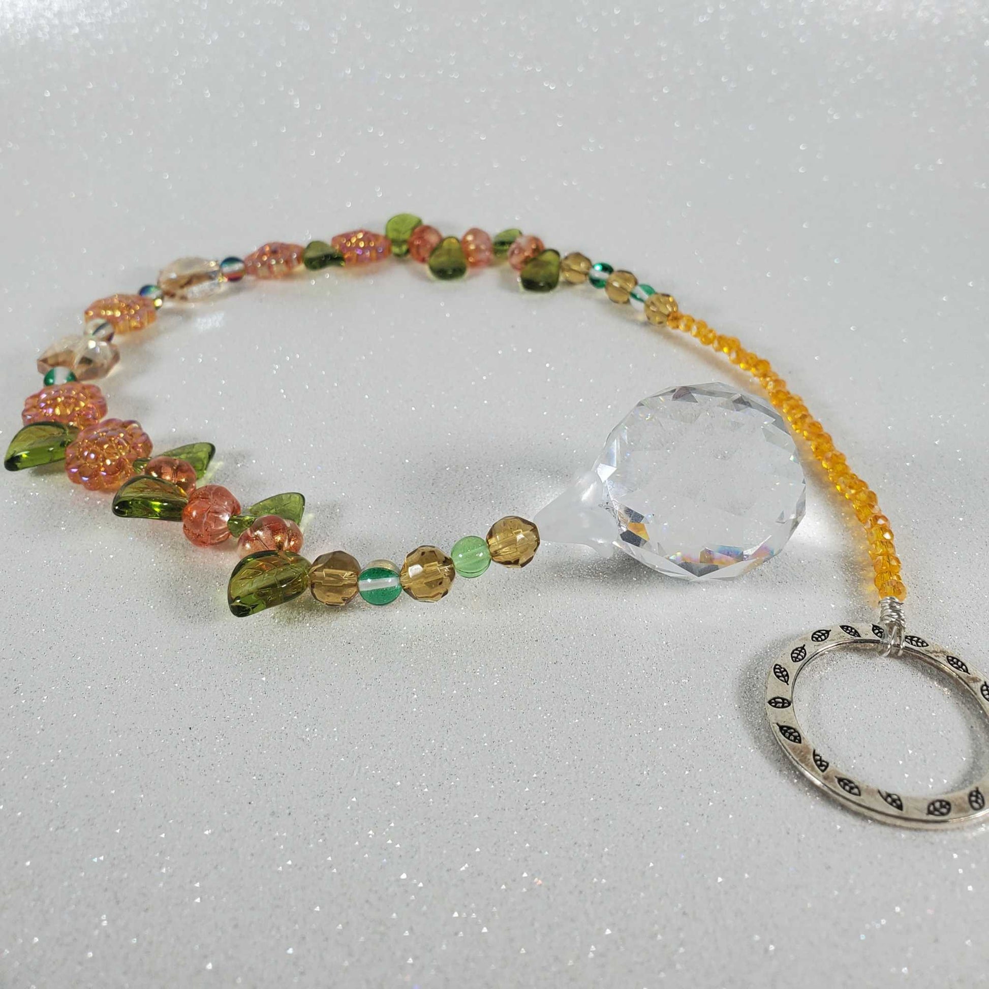 Crystal suncatcher with orange sunflower beads, green glass accents, yellow crystals, and a clear drop prism.