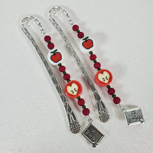 Silver bookmark with red and white apple designs on a light gray background