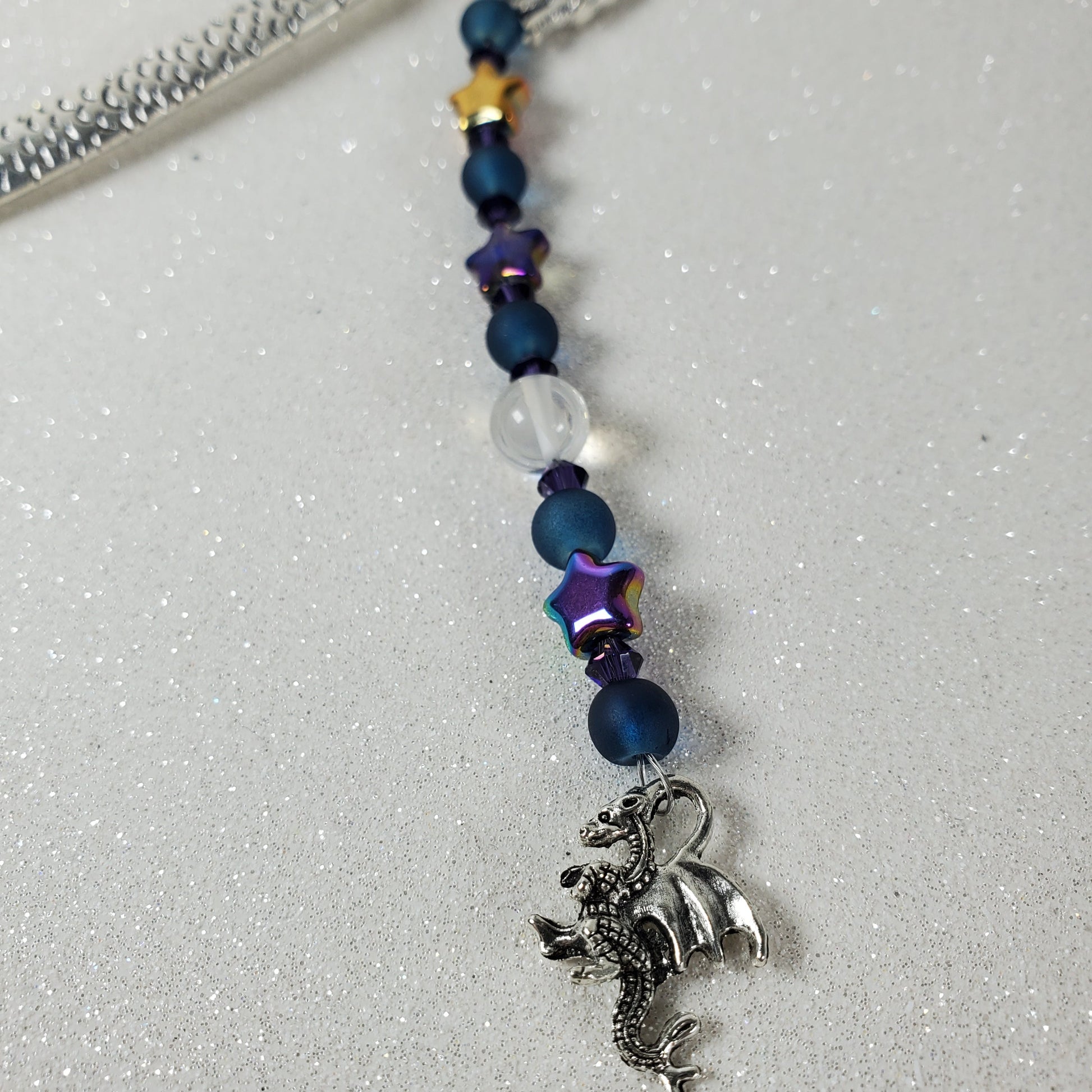 Bookmark with colorful beads and a dragon charm on a light gray background