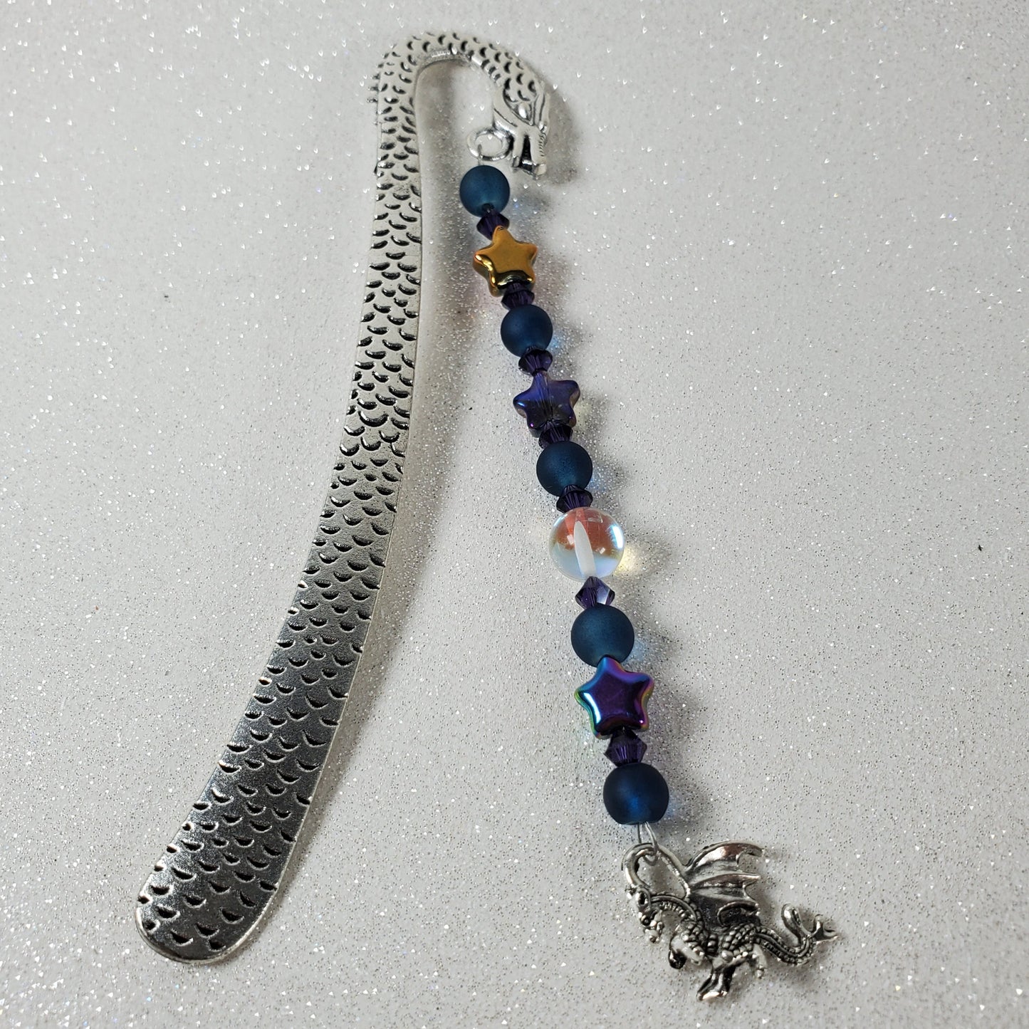 Metal bookmark with beaded extension on a gray background