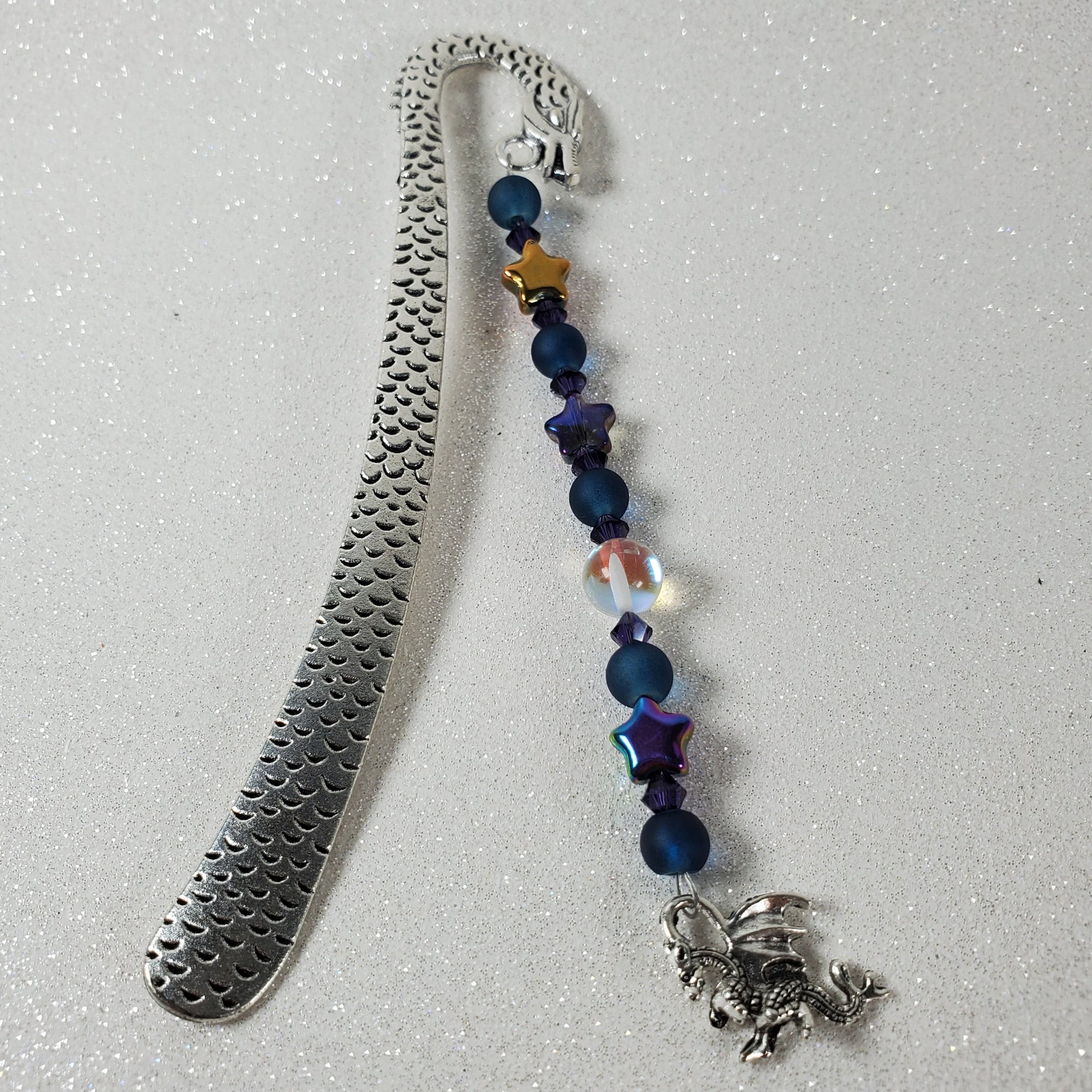 Metal bookmark with beaded extension on a gray background
