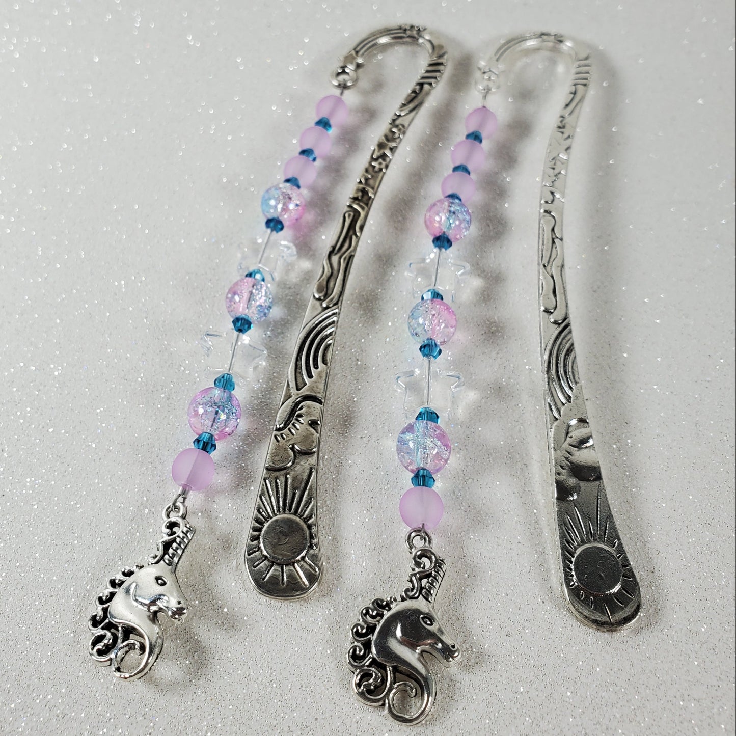 Silver bookmarks with beaded extensions on a textured white background