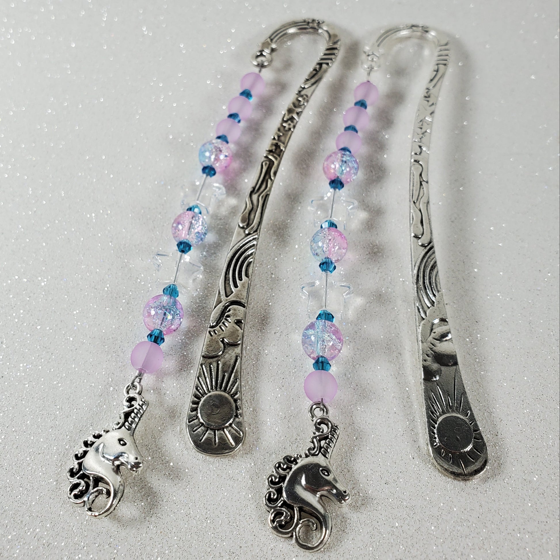 Silver bookmarks with beaded extensions on a textured white background