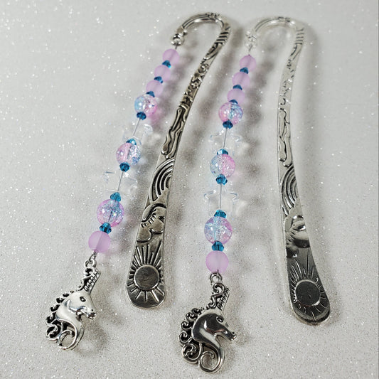 Silver bookmarks with beaded extensions on a textured white background