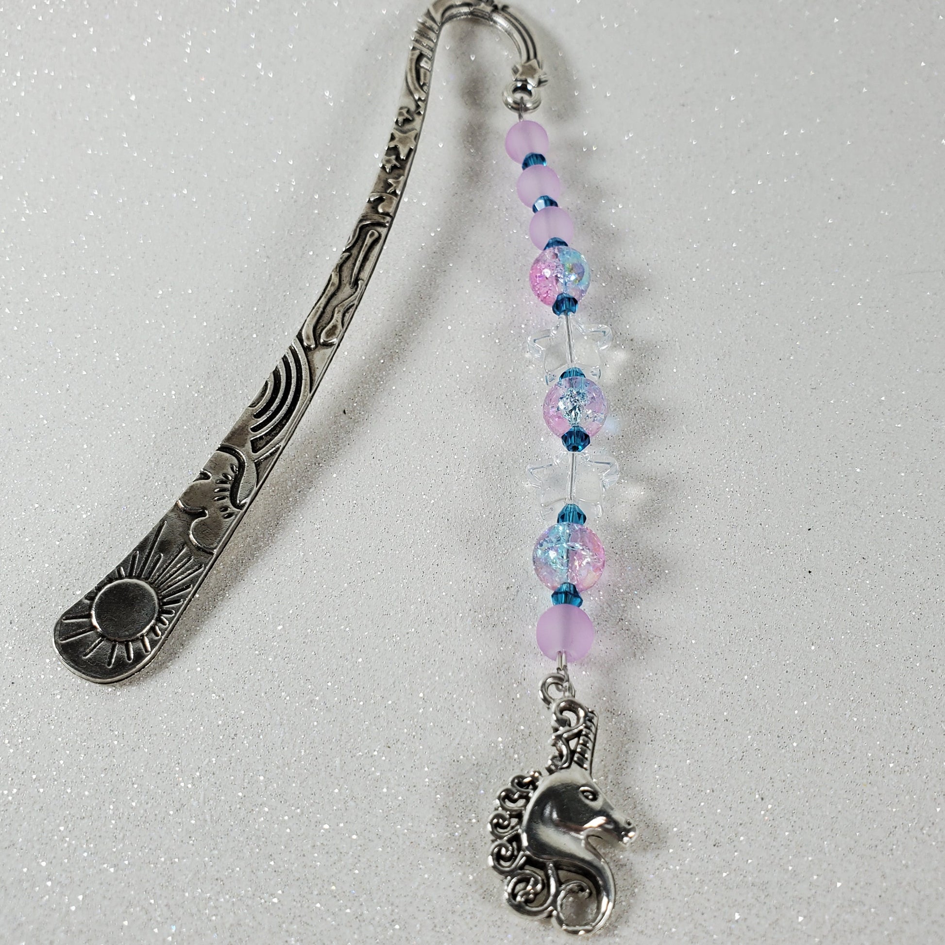 Decorative silver bookmark with beaded chain on a light gray background