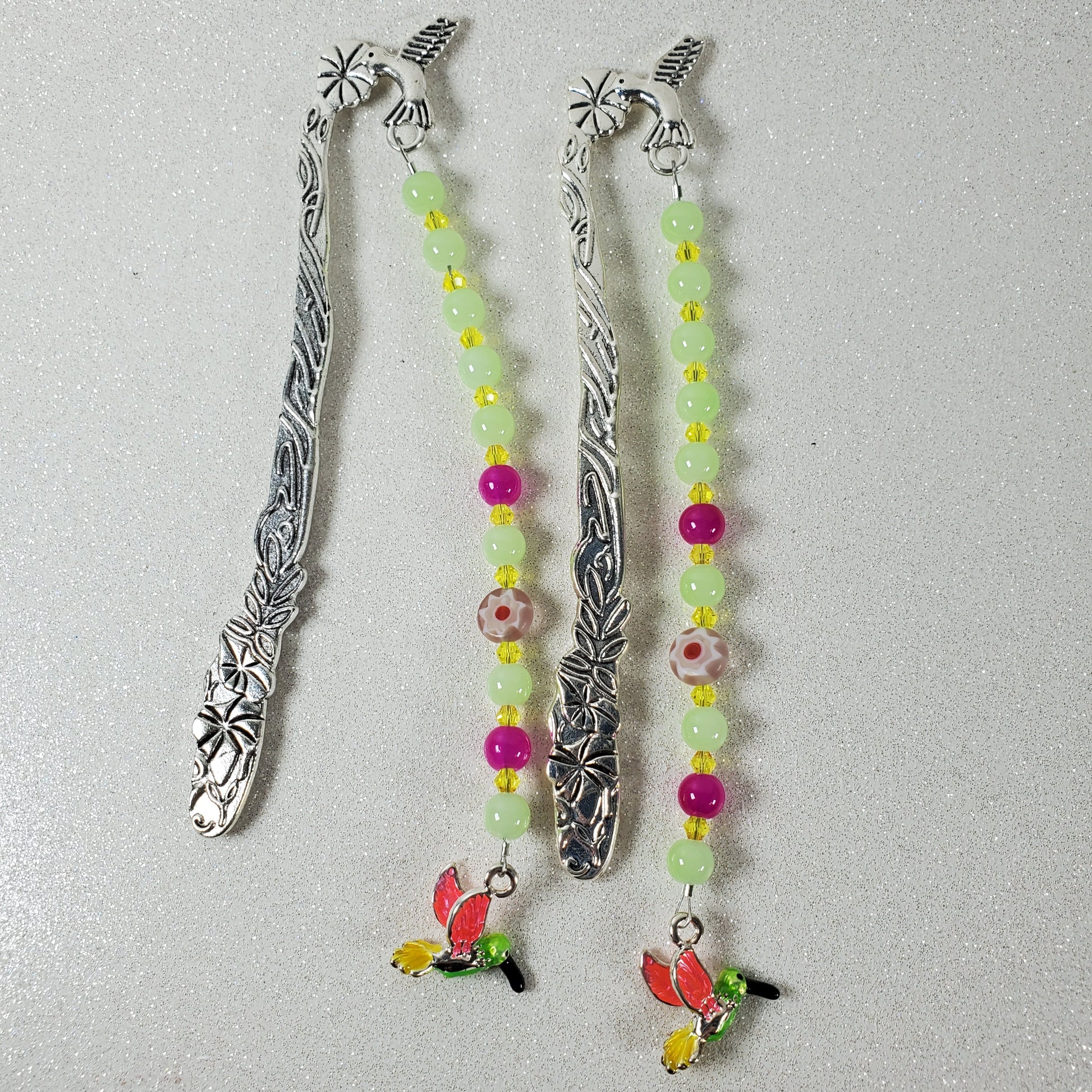Two silver bookmarks with beaded ends on a gray background
