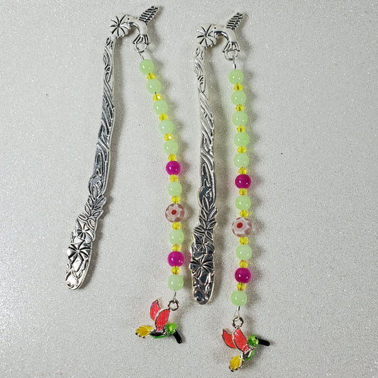 Two silver bookmarks with beaded ends on a gray background