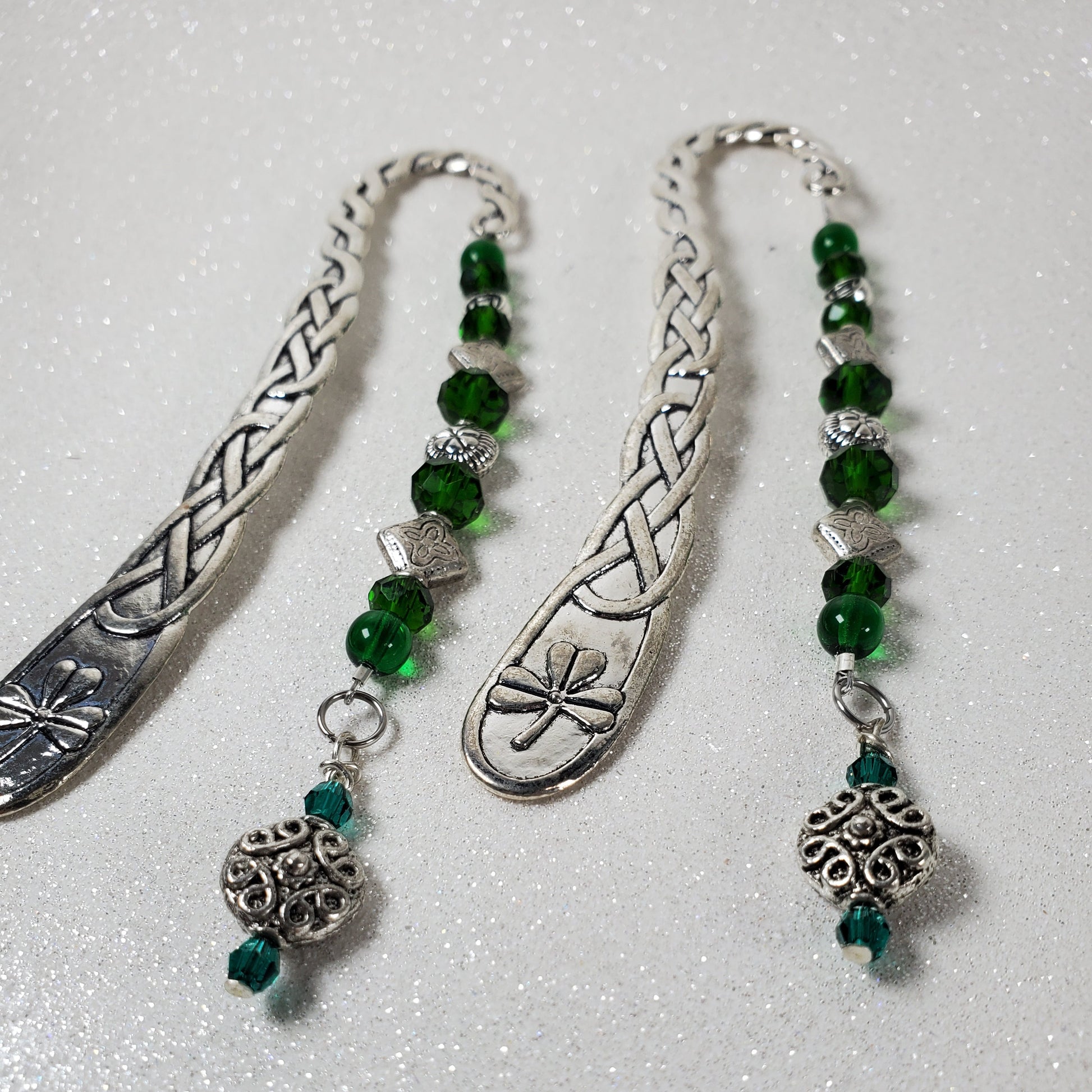 Two silver bookmarks with green beads on a white background