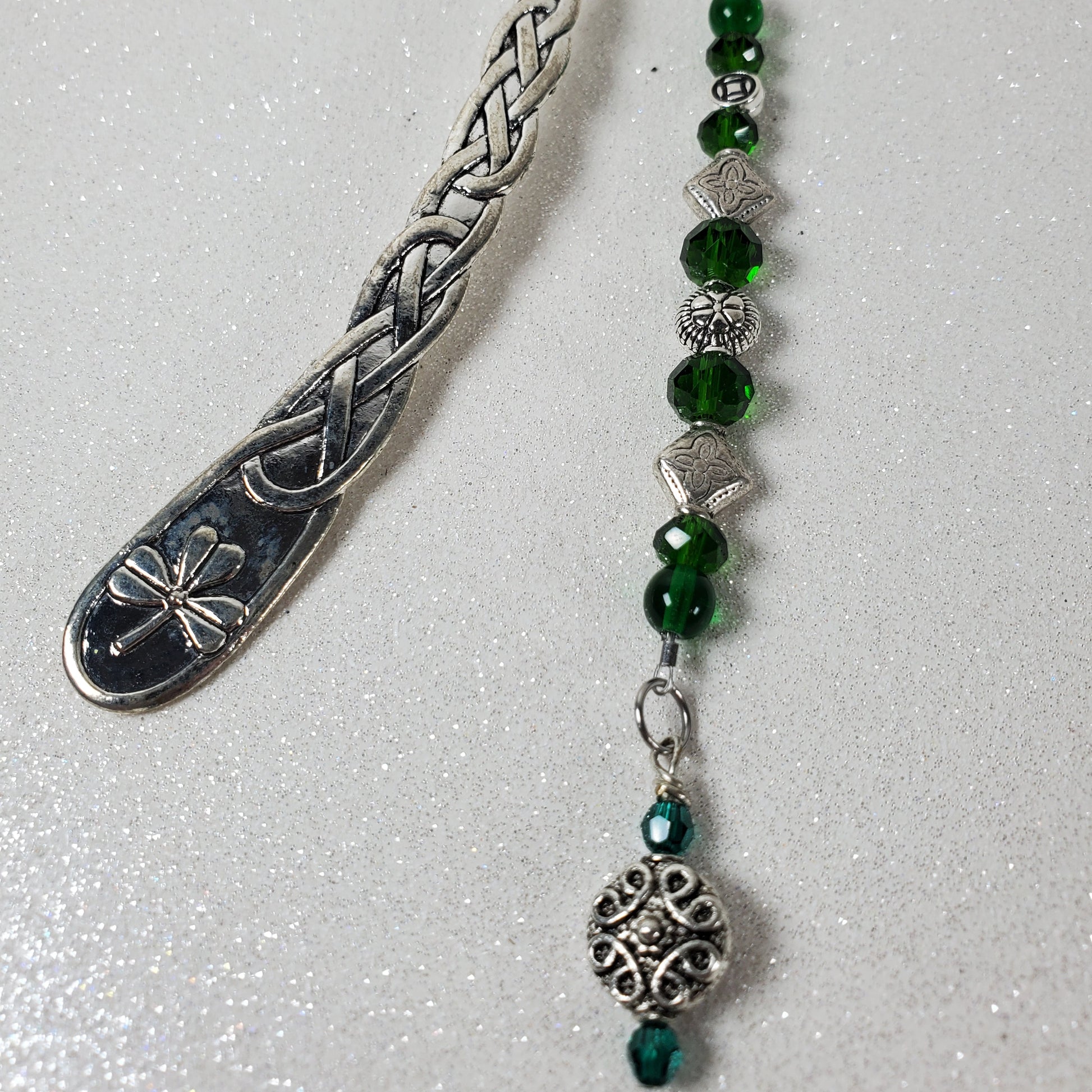 Silver bookmark with green beads on a white background