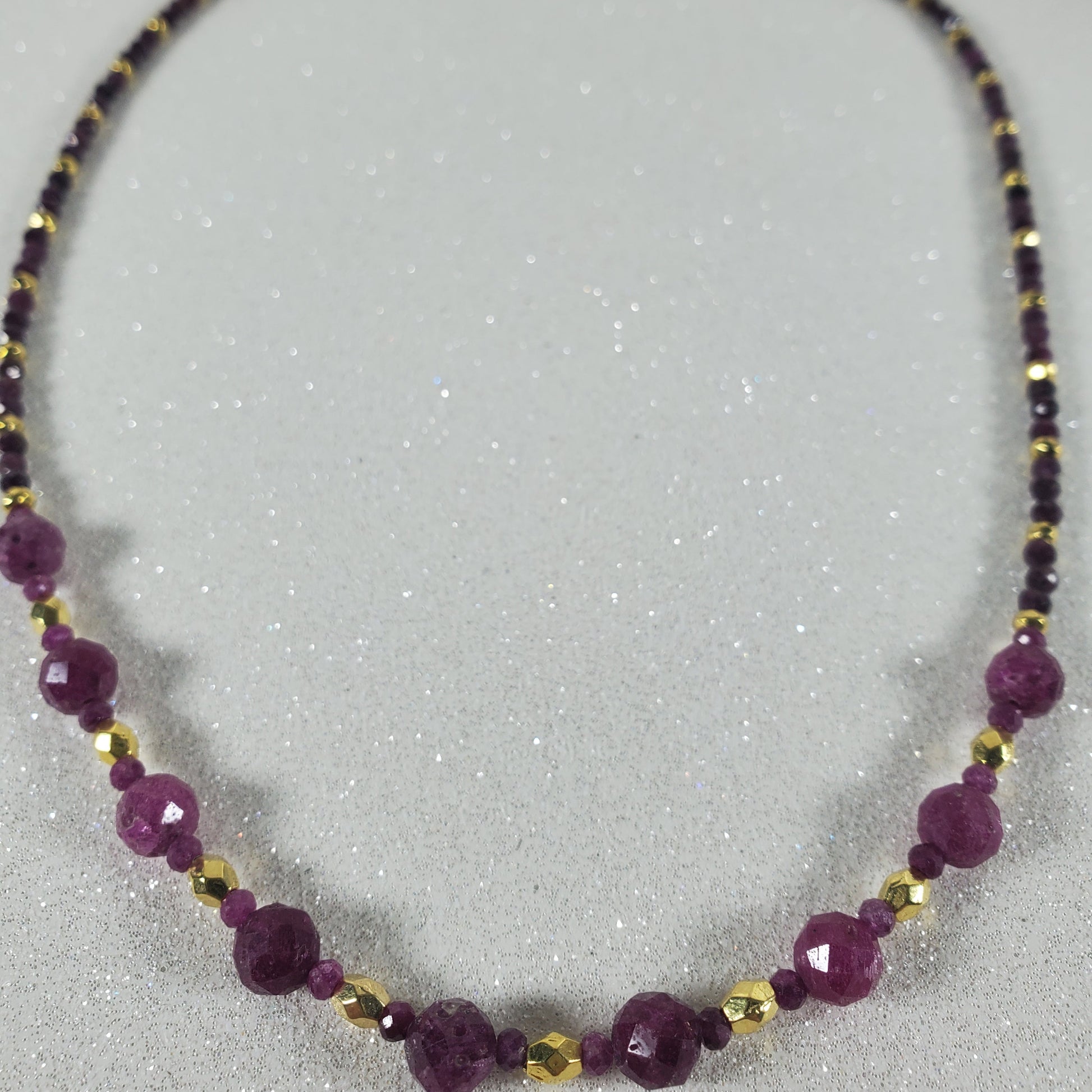 Necklace with Ruby beads and gold accents on a gray background