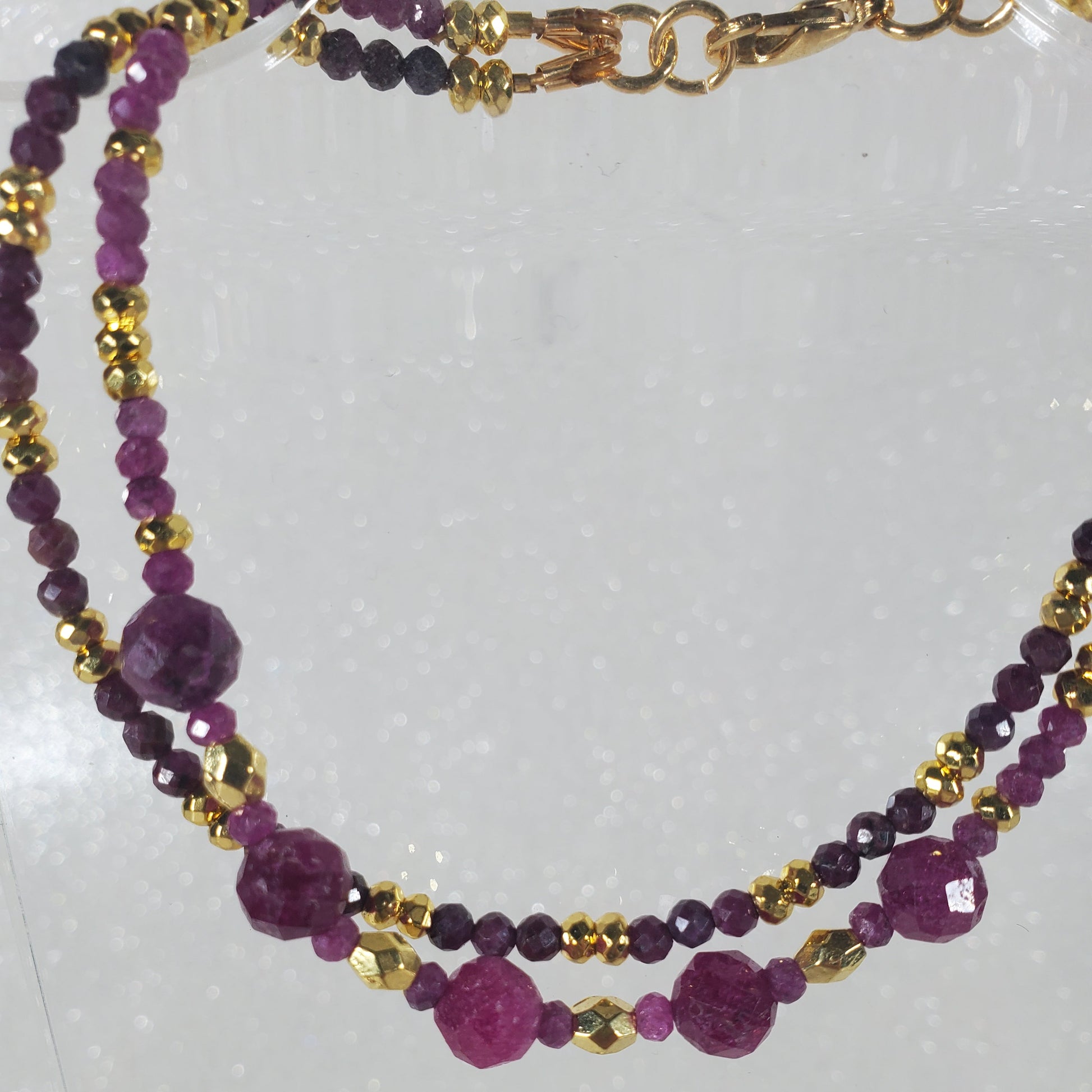 Bracelet with Ruby beads and gold accents on a white background