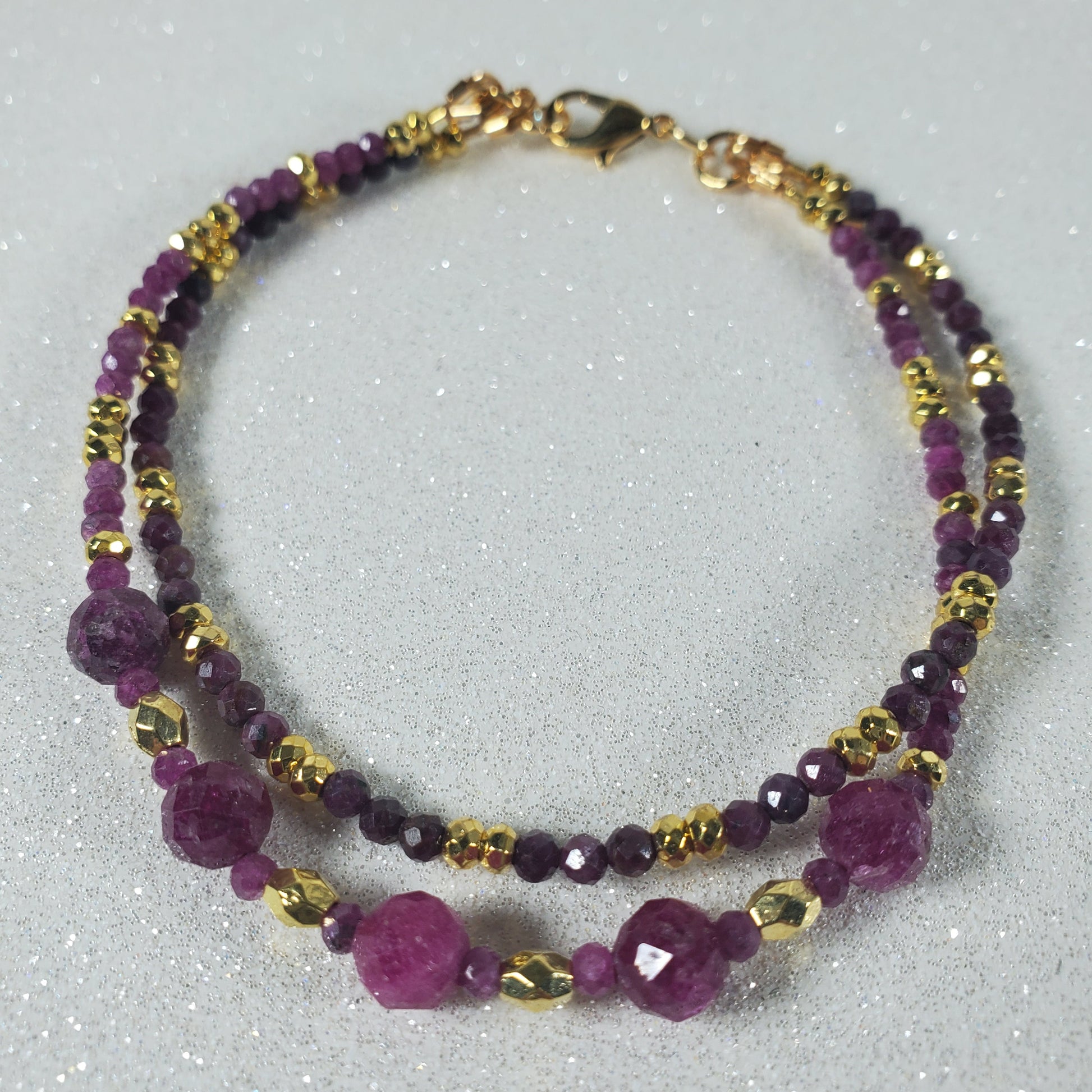 Beaded Bracelet with Ruby and gold beads on a gray background