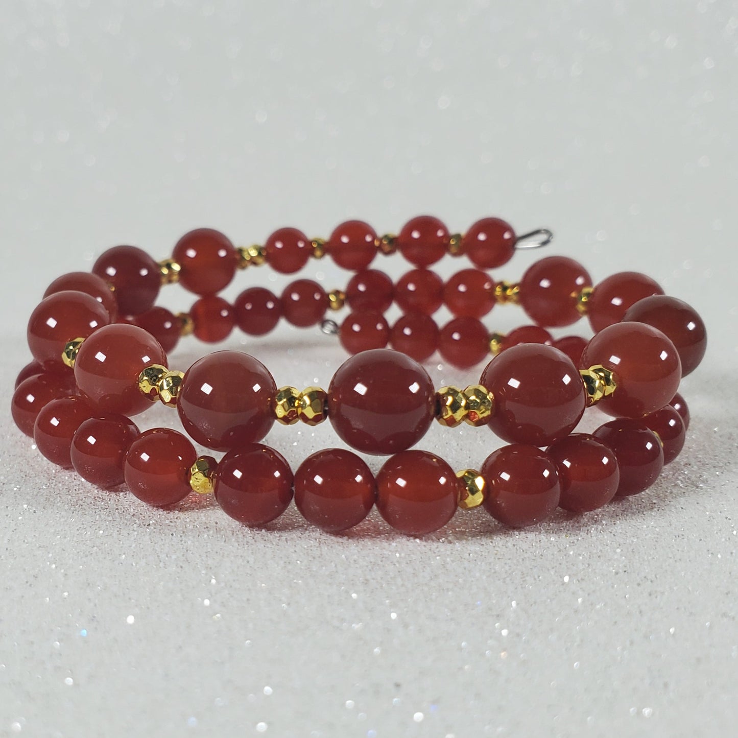 Red beaded bracelet with gold accents on a white background
