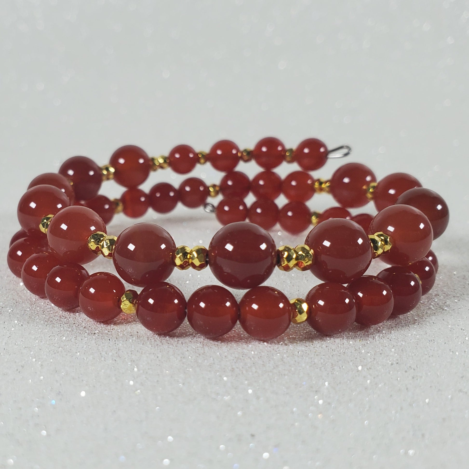 Red beaded bracelet with gold accents on a white background