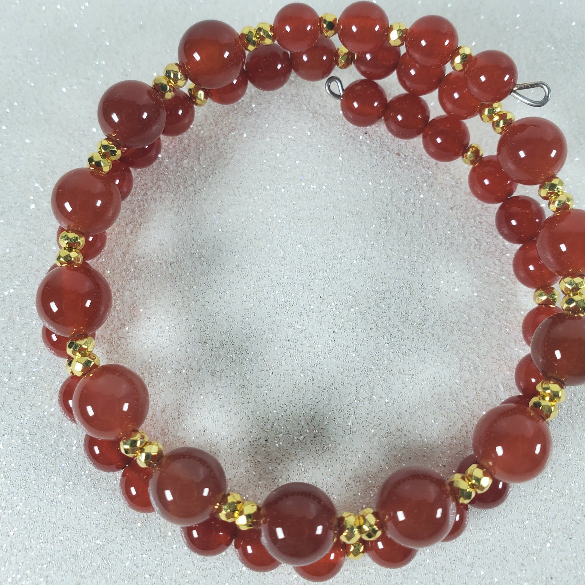 Red beaded bracelet with gold accents on a light gray background