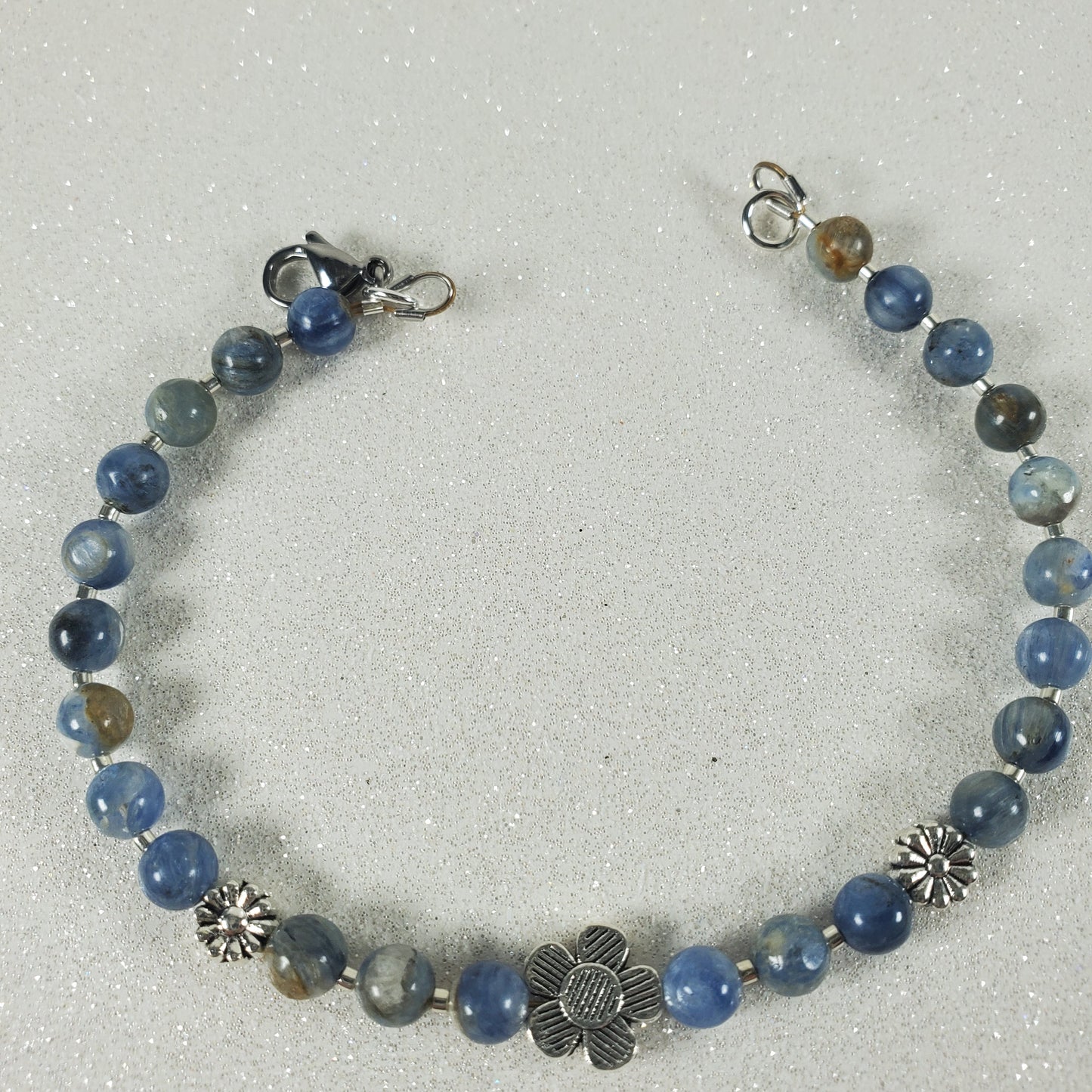 Beaded bracelet with blue Kyanite and silver flowers on a light gray background
