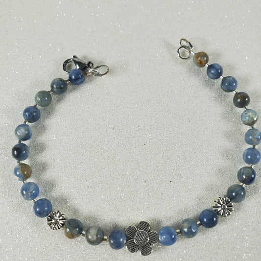 Beaded bracelet with blue Kyanite and silver flowers on a light gray background