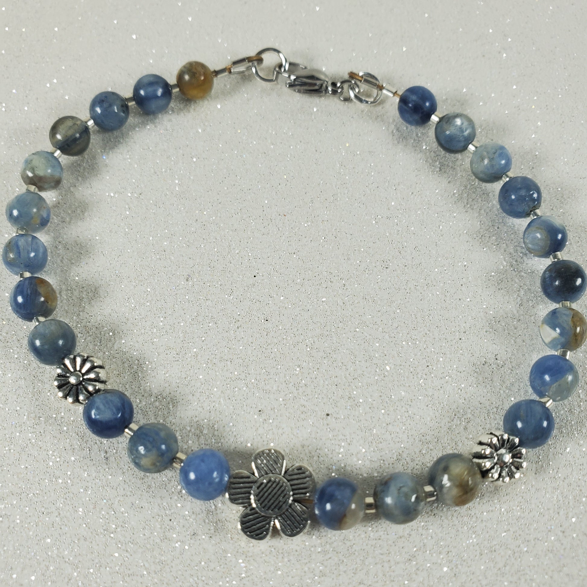 Bracelet with blue gemstone beads and silver charms on a white background