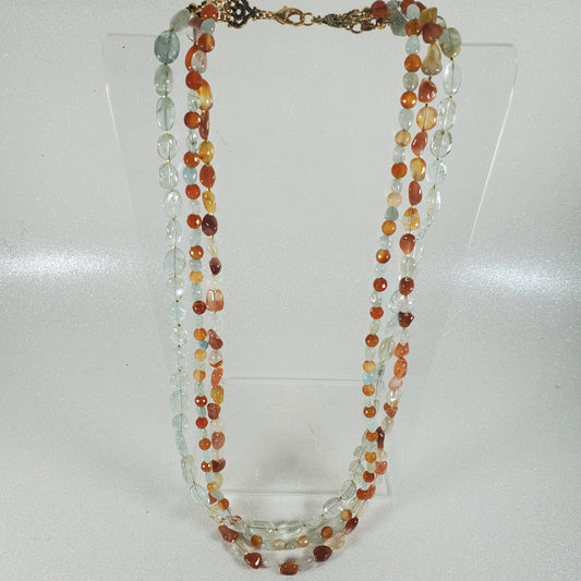 Multicolored beaded necklace on a clear stand against a white background