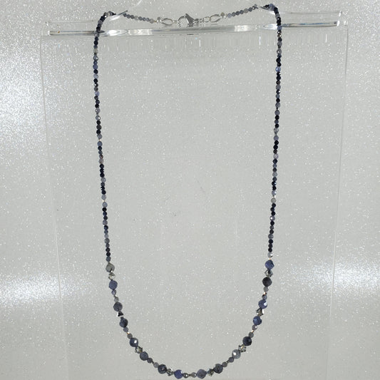 Necklace with small beads on a clear stand against a light gray background