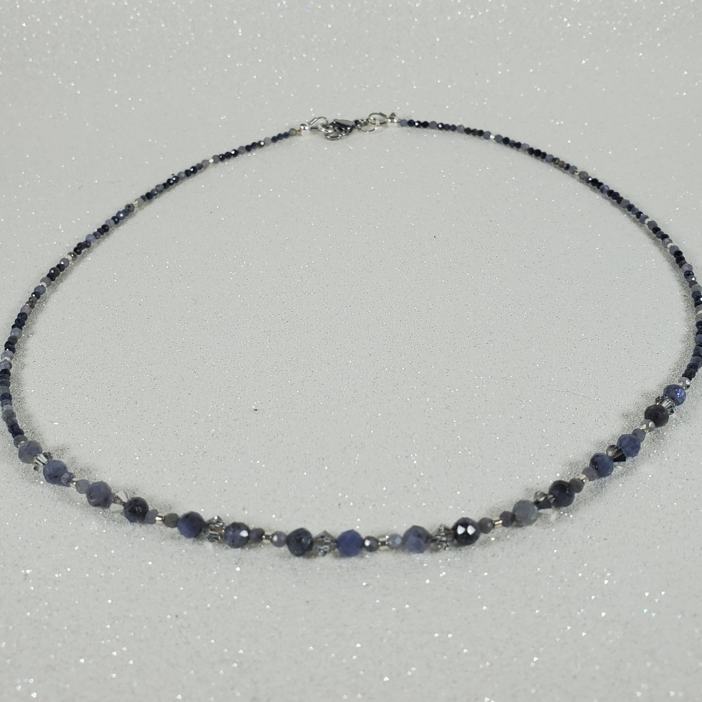 Necklace with blue and silver beads on a light gray background