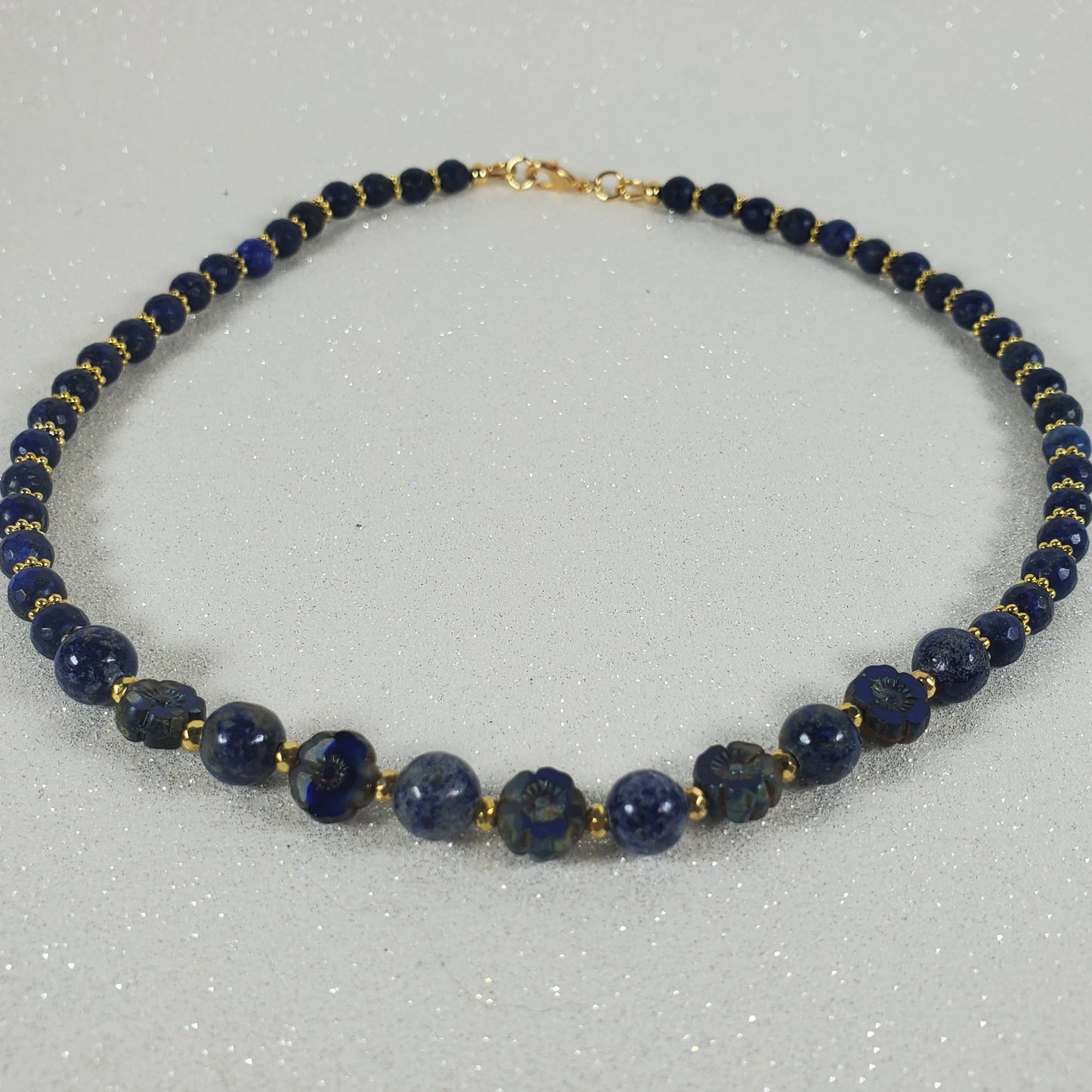 Necklace with blue beads and gold accents on a light gray background