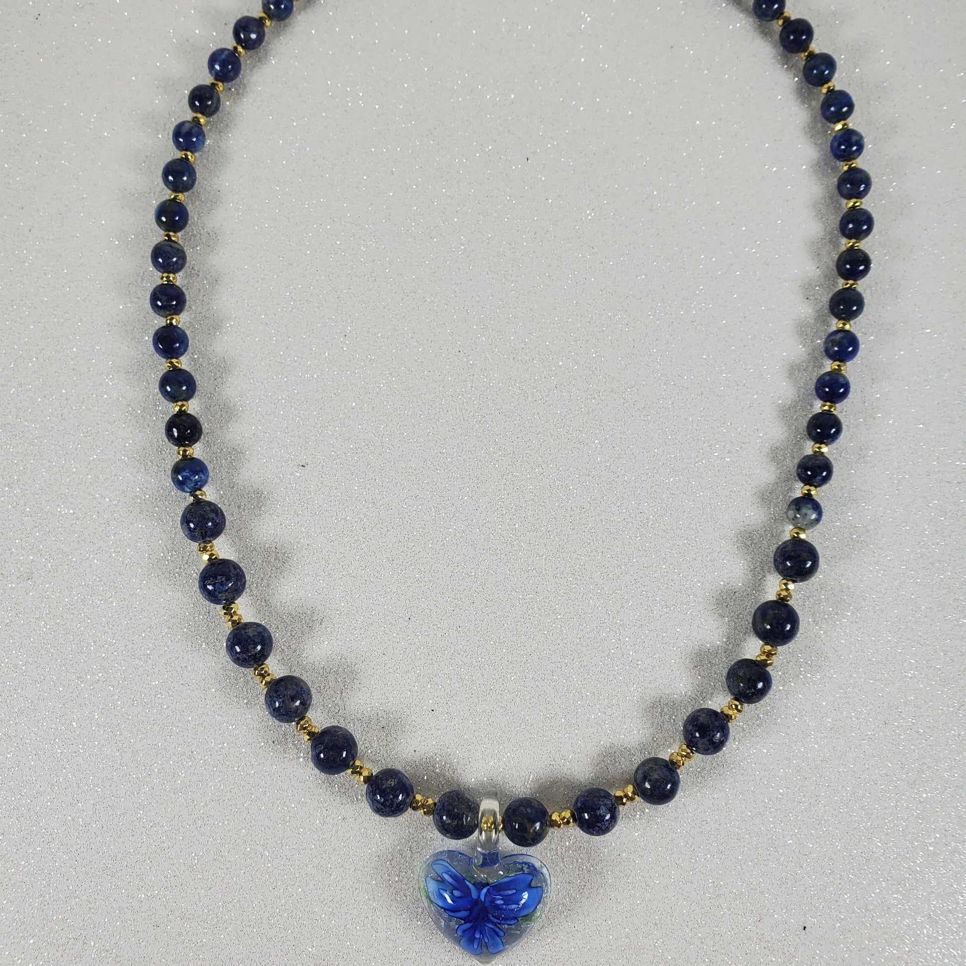 Necklace with blue beads and a blue flower pendant on a light gray background