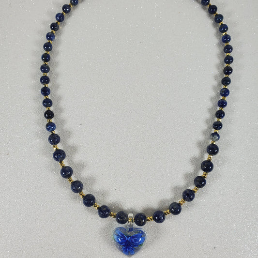 Necklace with blue beads and a blue flower pendant on a light gray background