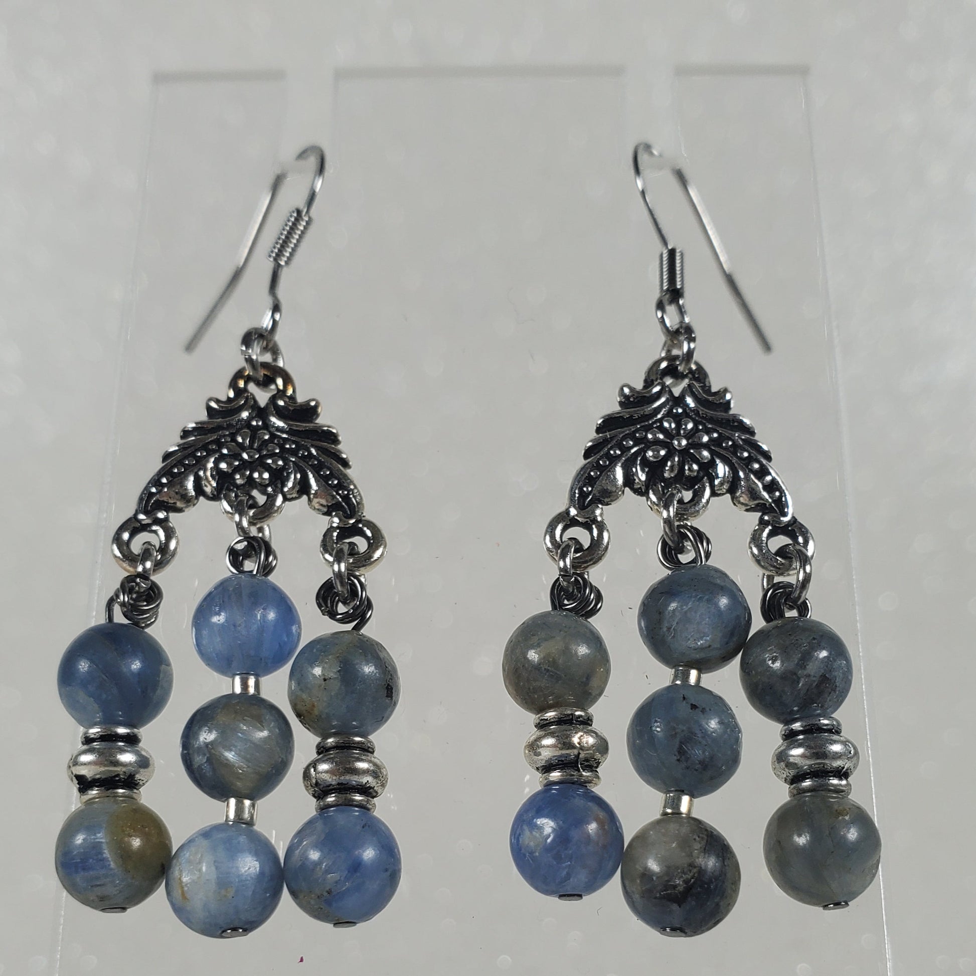 Pair of blue beaded earrings on a clear stand against a white background