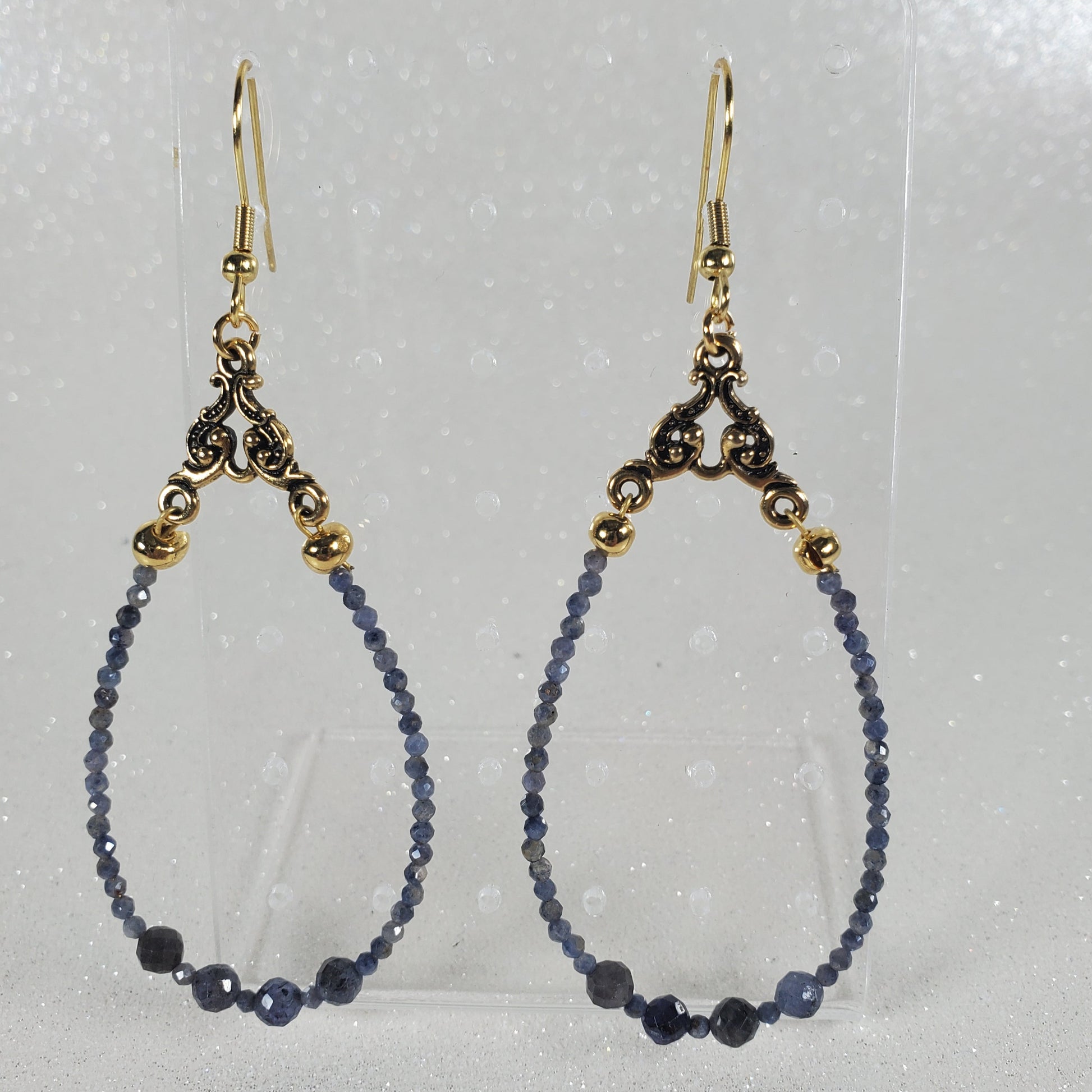 Beaded earrings with gold clasp on a clear card against a gray background