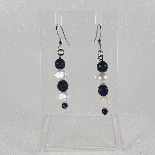 Pair of earrings on a clear plastic stand on a light gray background