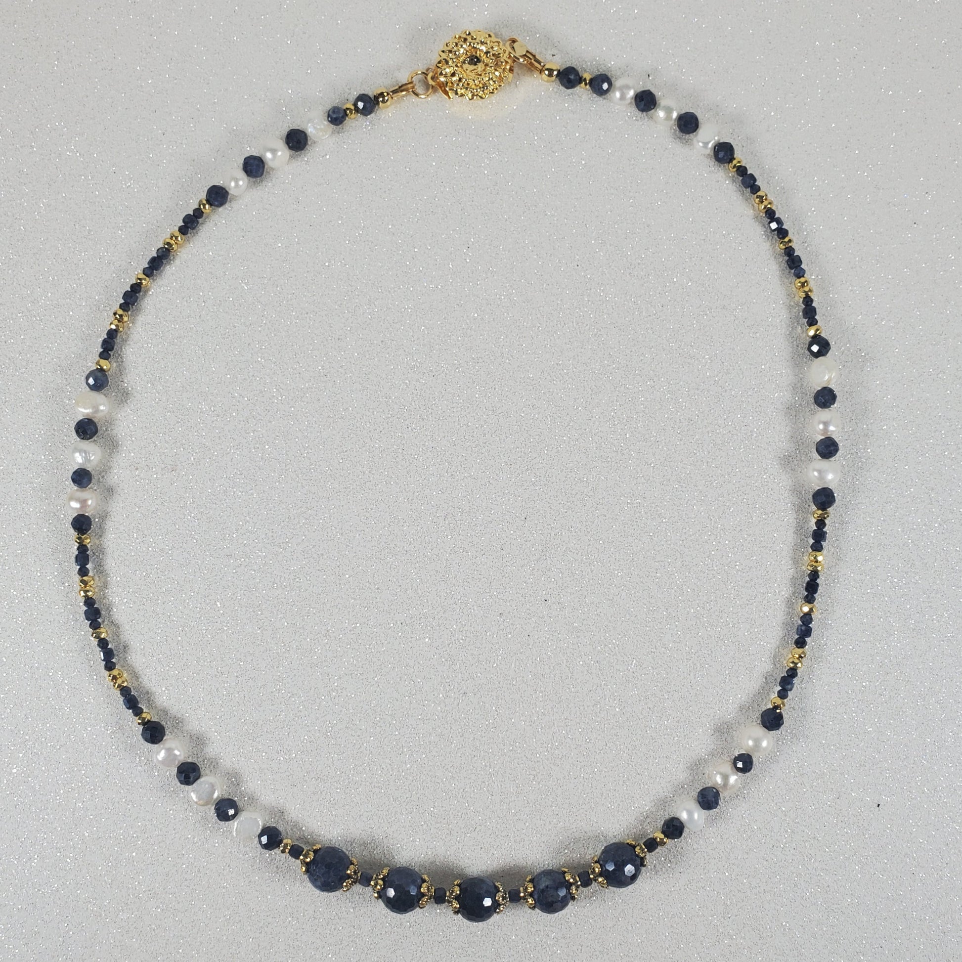 Necklace with blue and gold beads on a light gray background