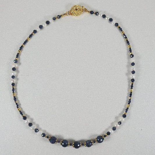 Necklace with blue and gold beads on a light gray background