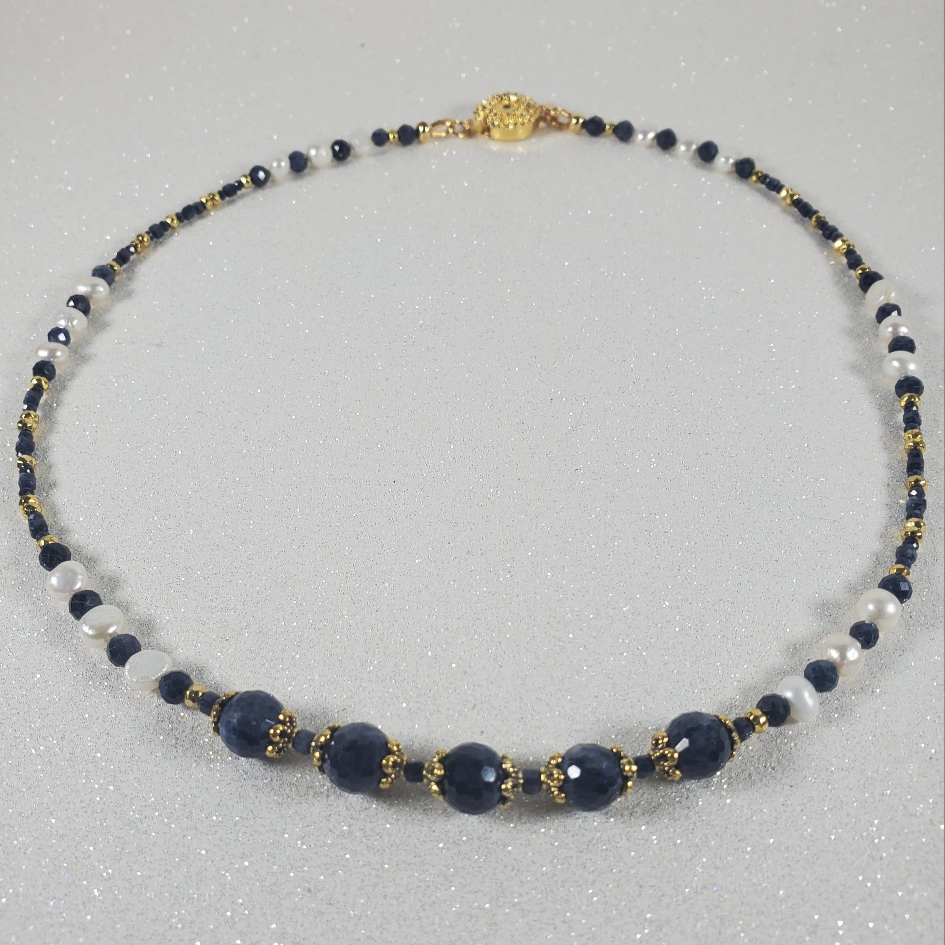 Necklace with blue, white, and gold beads on a gray background