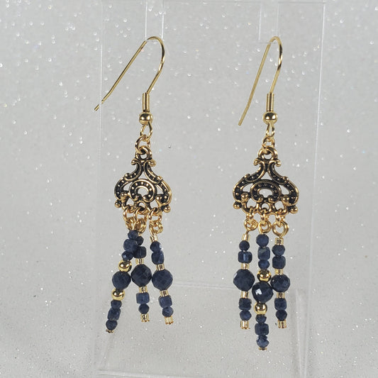 Pair of gold and blue beaded earrings on a clear card with a white background