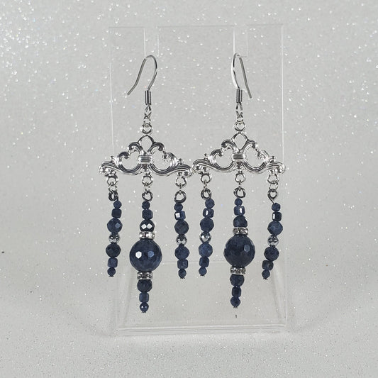 Pair of blue beaded earrings on a clear card against a light gray background