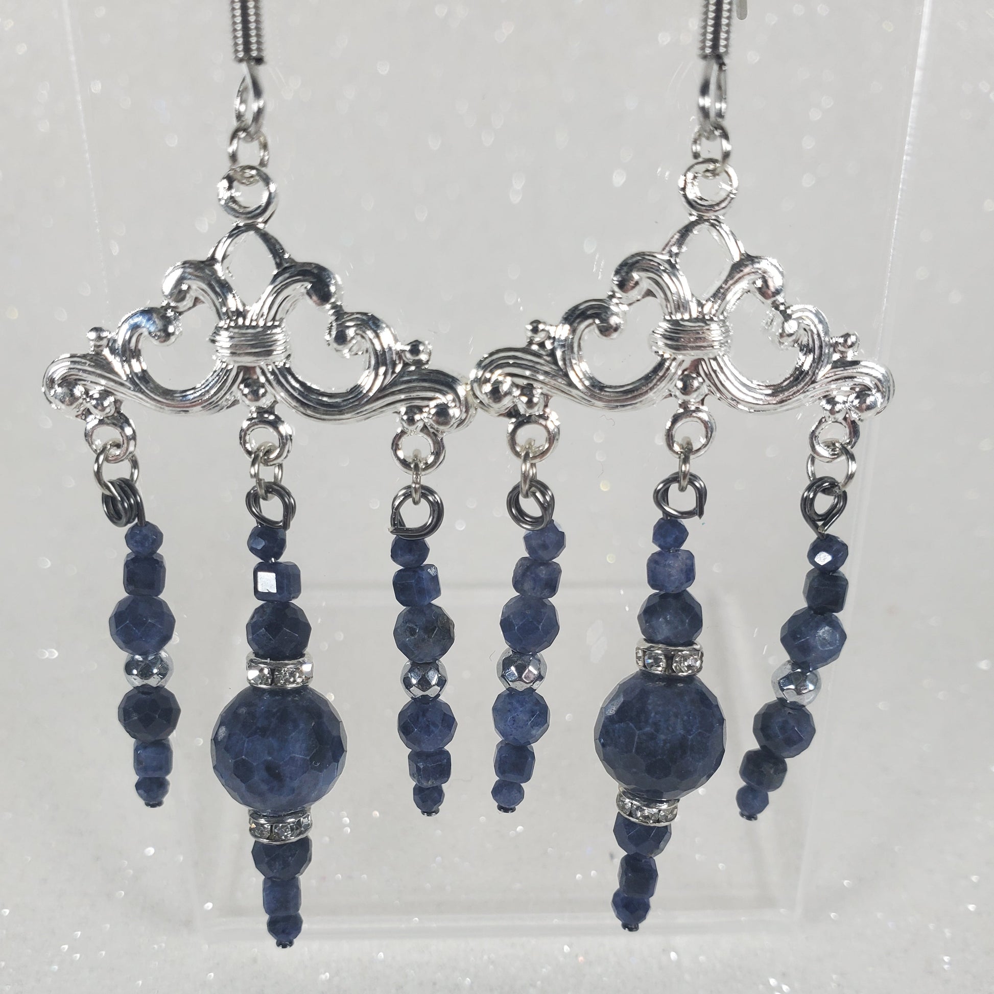 Silver and blue beaded hair accessories on a clear stand against a light gray background