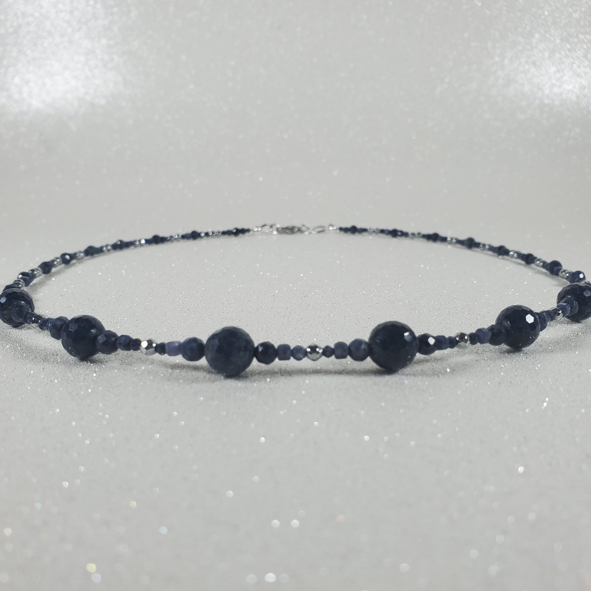 Beaded necklace with dark beads on a light gray background