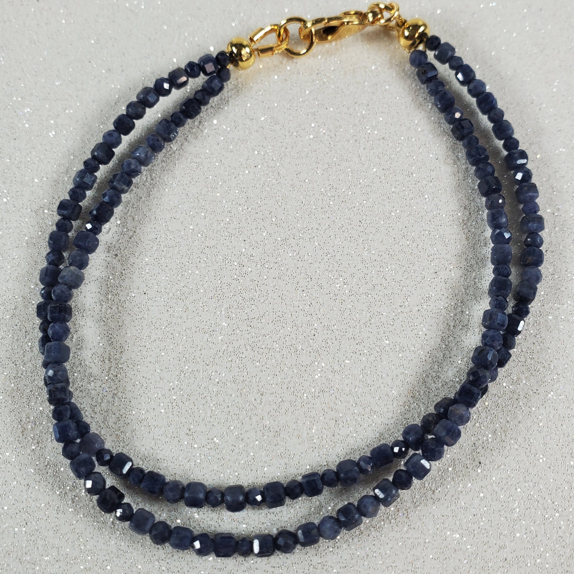 Navy blue beaded necklace with gold clasp on a light gray background