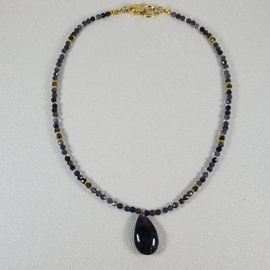 Beaded necklace with a Iolite teardrop pendant on a white background